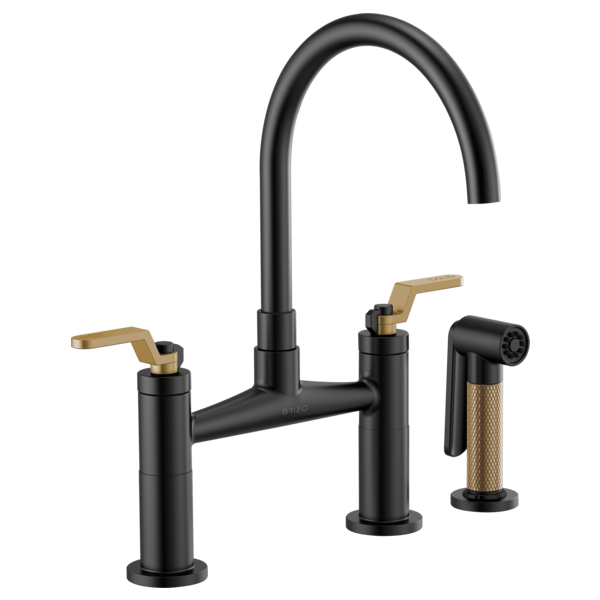 Black bridge faucet with curved arc spout, gold lever handles, and matching side spray with textured grip.