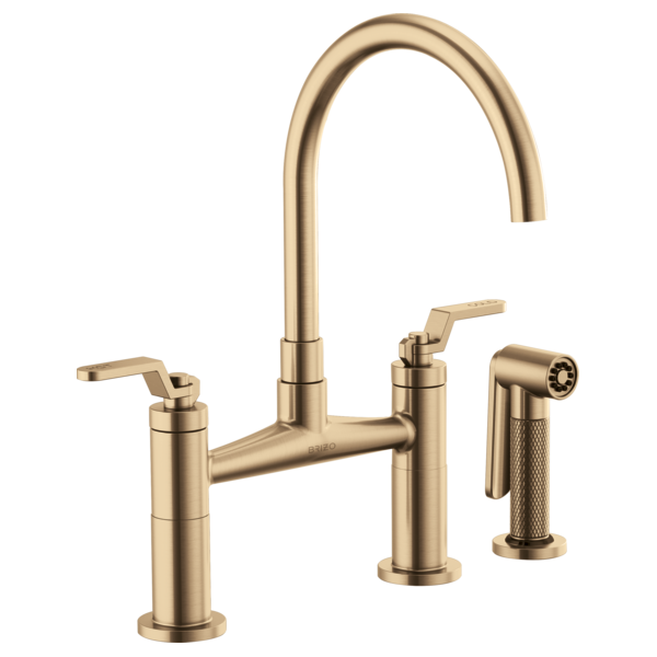 Champagne bronze bridge faucet with curved arc spout, dual lever handles, and side sprayer attachment.