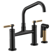 Black bridge faucet with angled spout, knurled brass handles, and matching brass side spray.