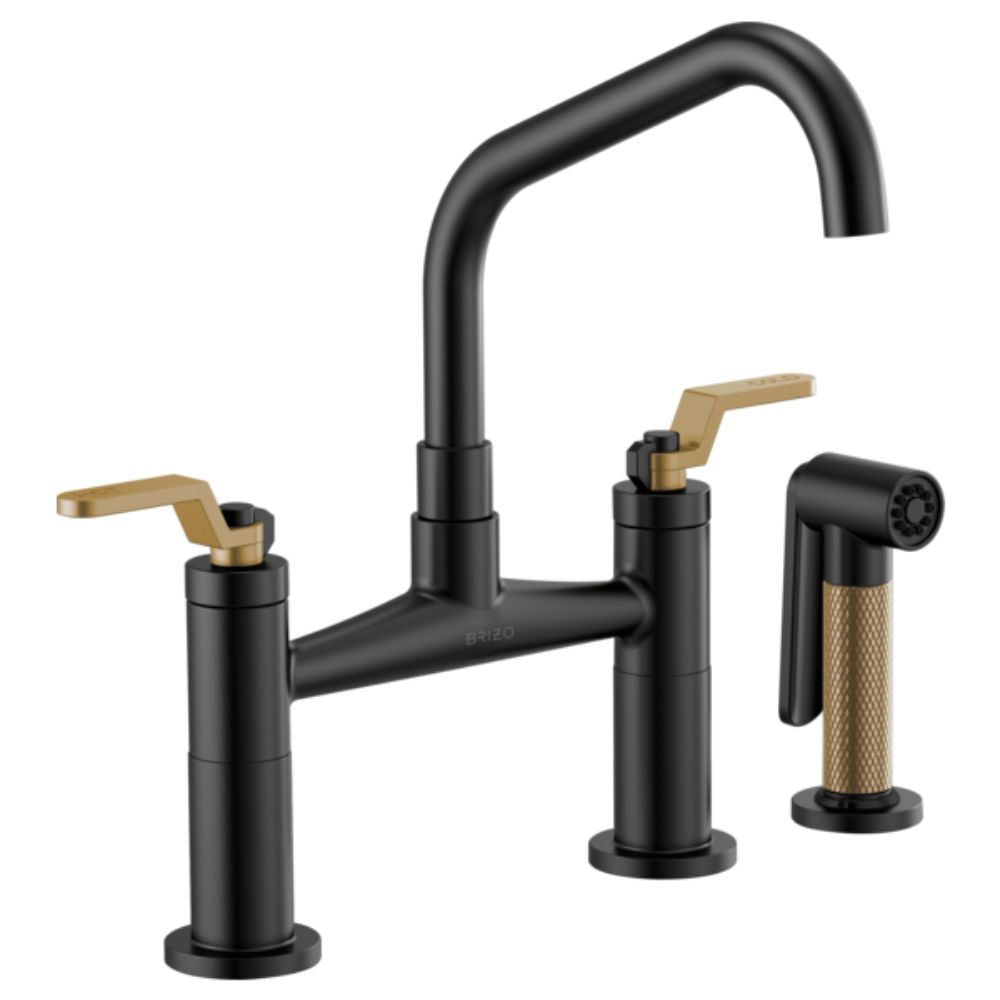 Black bridge faucet with angled spout, brass lever handles, and matching side spray.