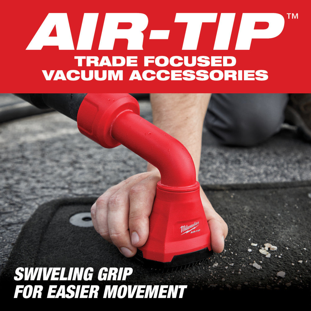Red Milwaukee AIR-TIP vacuum tool with swiveling grip being held over car floor mat during cleaning demonstration.