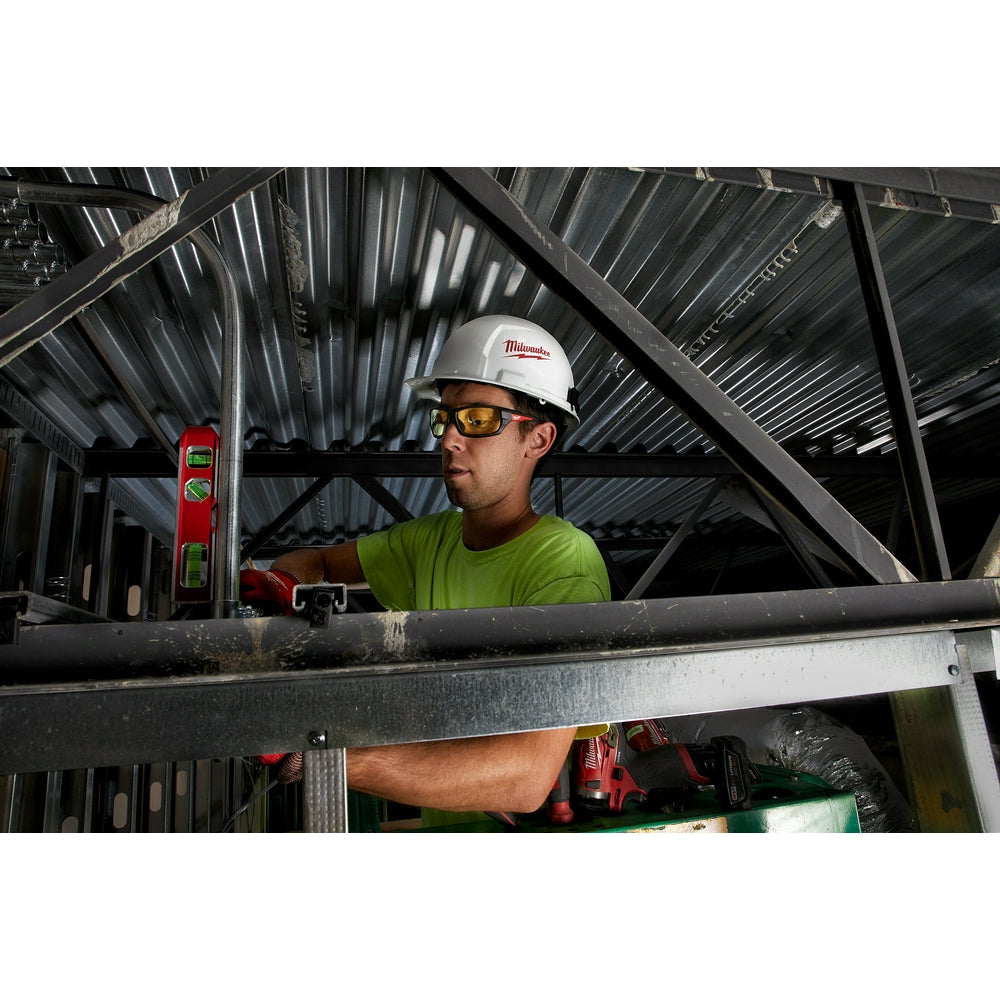 Yellow-lensed safety glasses worn by worker on construction site.