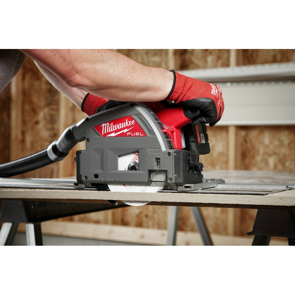 Milwaukee FUEL track saw with red and black body cutting through fiber cement board on a work surface.