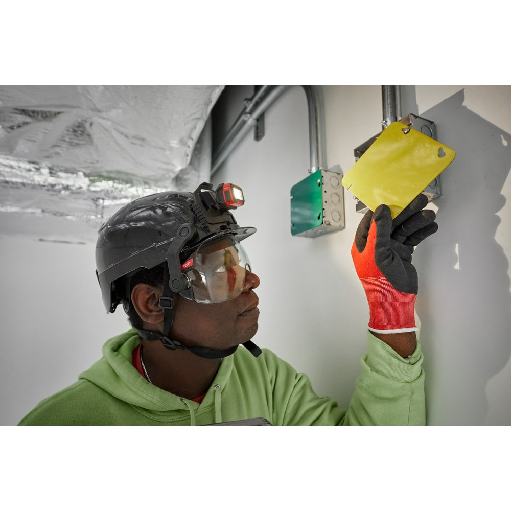 Worker wearing black helmet with red headlamp mounted on front, holding yellow BOLT mount accessory against wall.