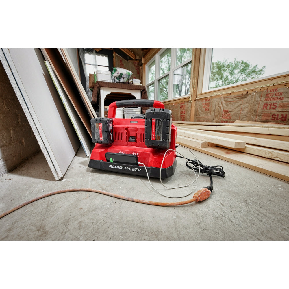 Red and black Milwaukee rapid charger unit with six charging bays and attached power cord on concrete floor.