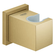 Brushed gold wall-mounted hand shower holder with curved cradle and Grohe branding.