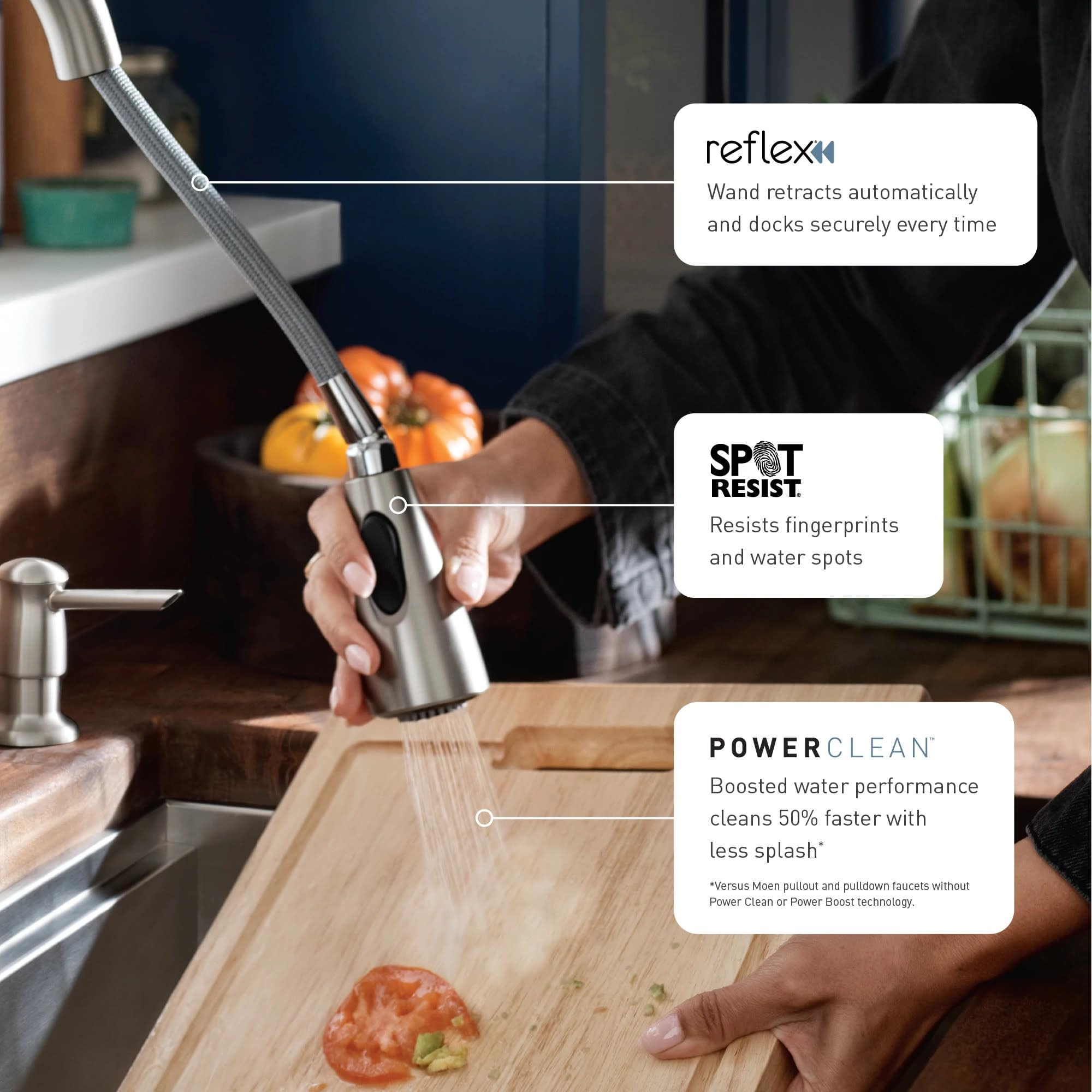 Stainless steel pulldown kitchen faucet with retractable wand spraying water over cutting board with vegetables.