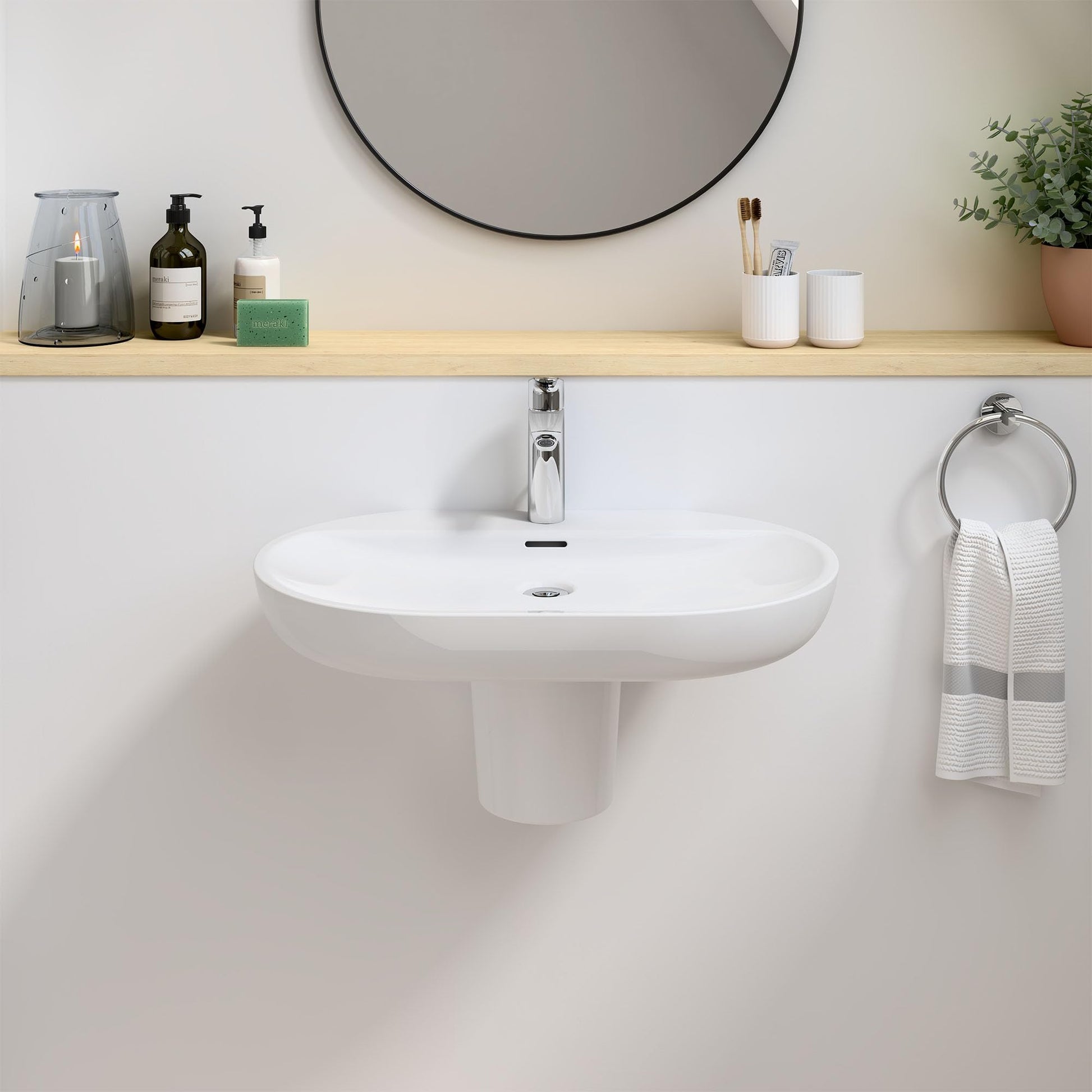 Chrome single-handle bathroom faucet with tall spout mounted on white round pedestal sink.