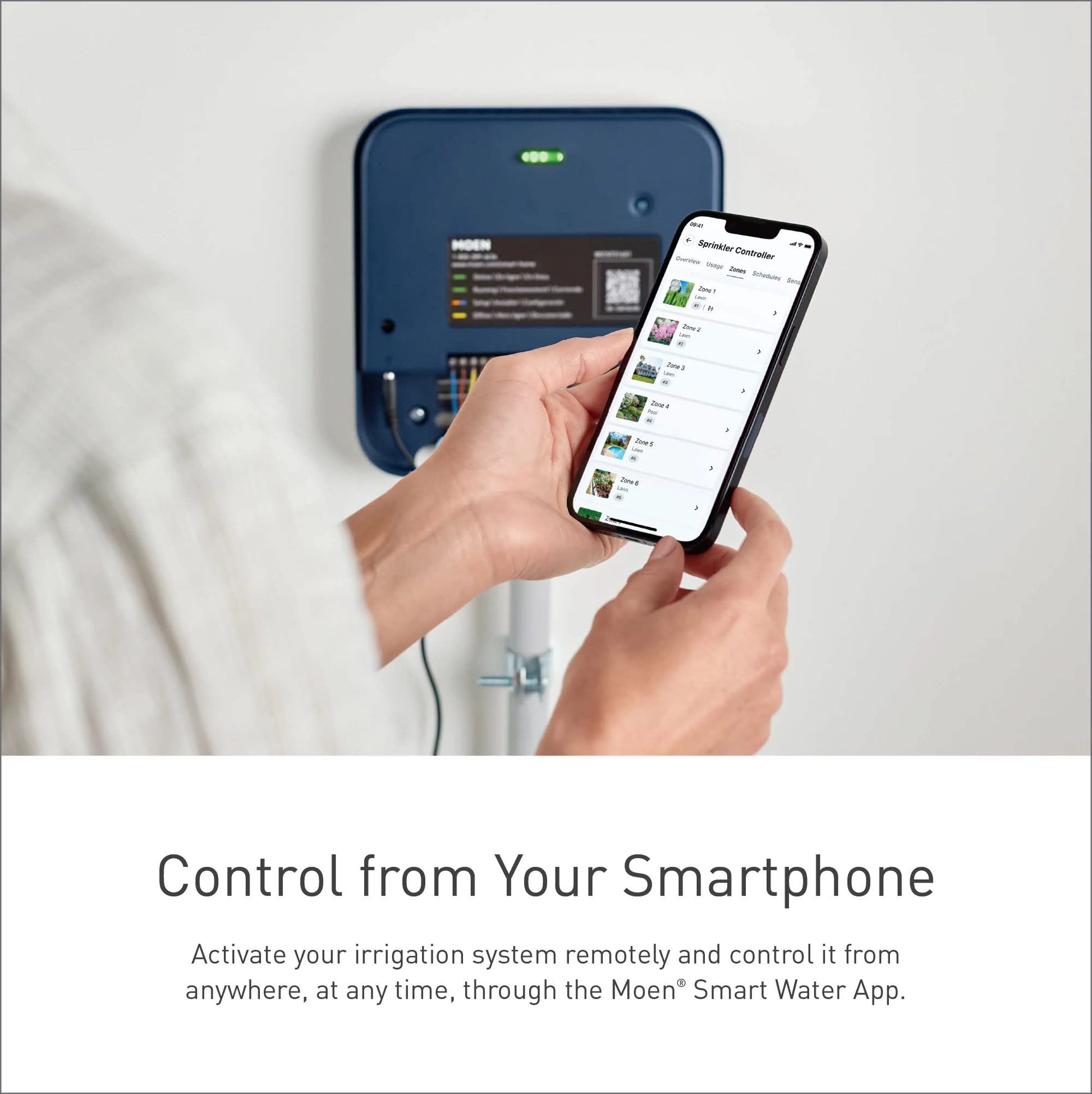 Blue Moen smart sprinkler controller mounted on wall with smartphone displaying sprinkler zone controls.