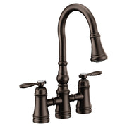 Oil rubbed bronze bridge kitchen faucet with two lever handles and pulldown sprayer head.