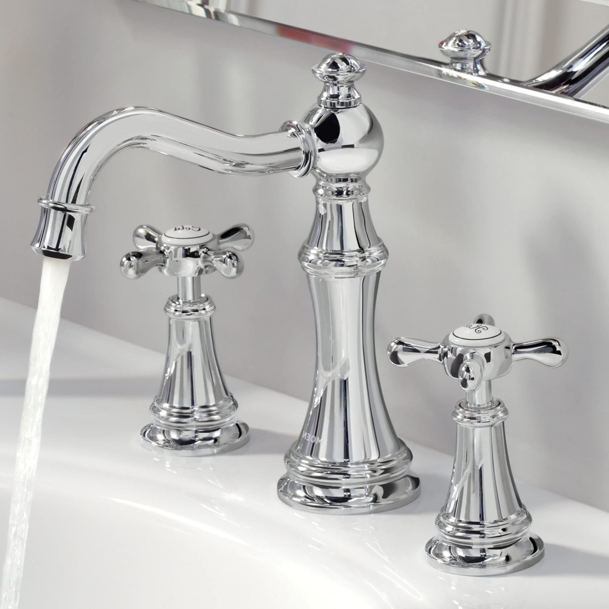 Chrome widespread bathroom faucet with curved spout and two cross handles, displayed on white sink.