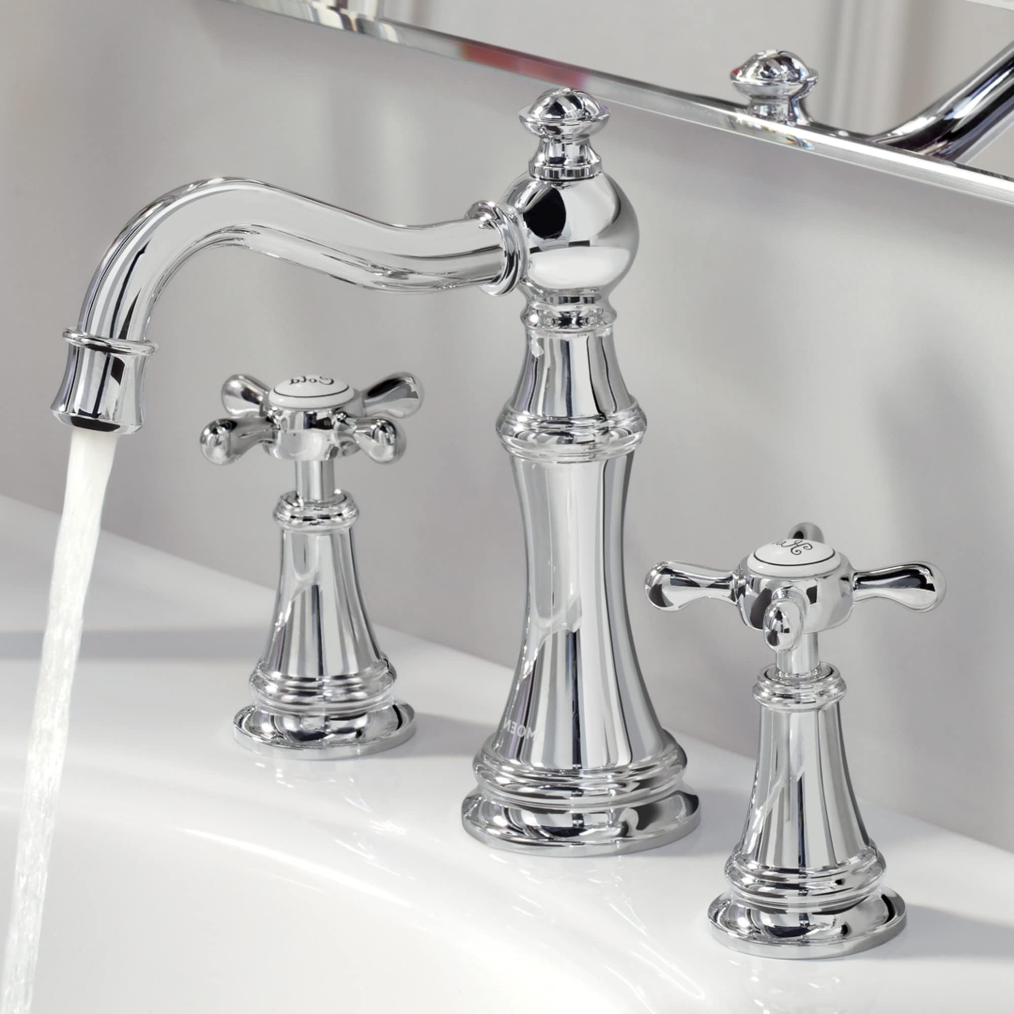 Chrome widespread bathroom faucet with curved spout and two cross handles, displayed on white sink.