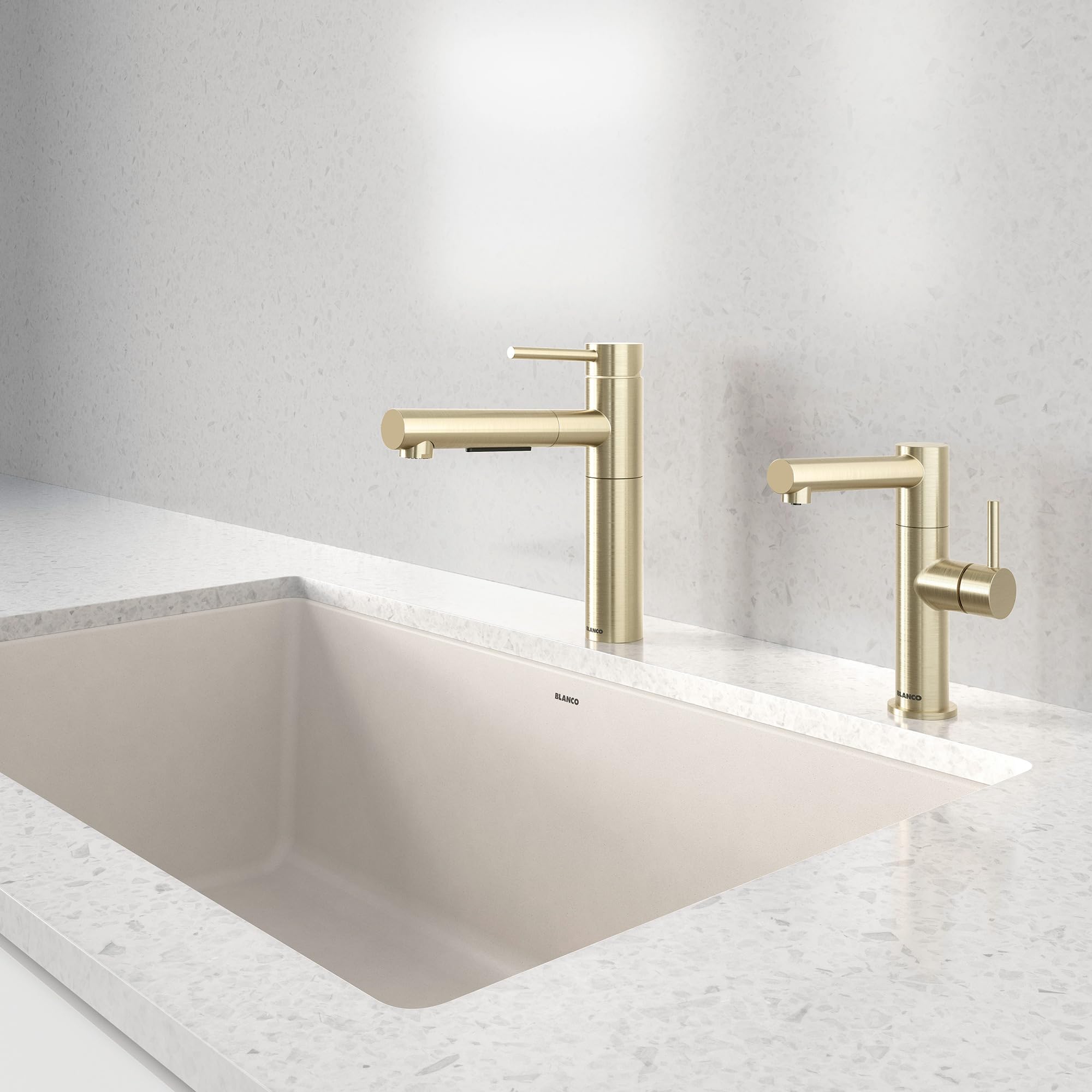 Satin gold pull-out kitchen faucet with tall spout mounted on white marble countertop above undermount sink.