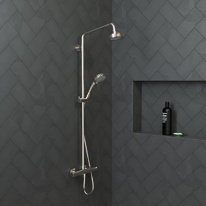 Polished nickel shower system with overhead rainfall head, handheld wand, and mixing valve mounted on gray tile wall.