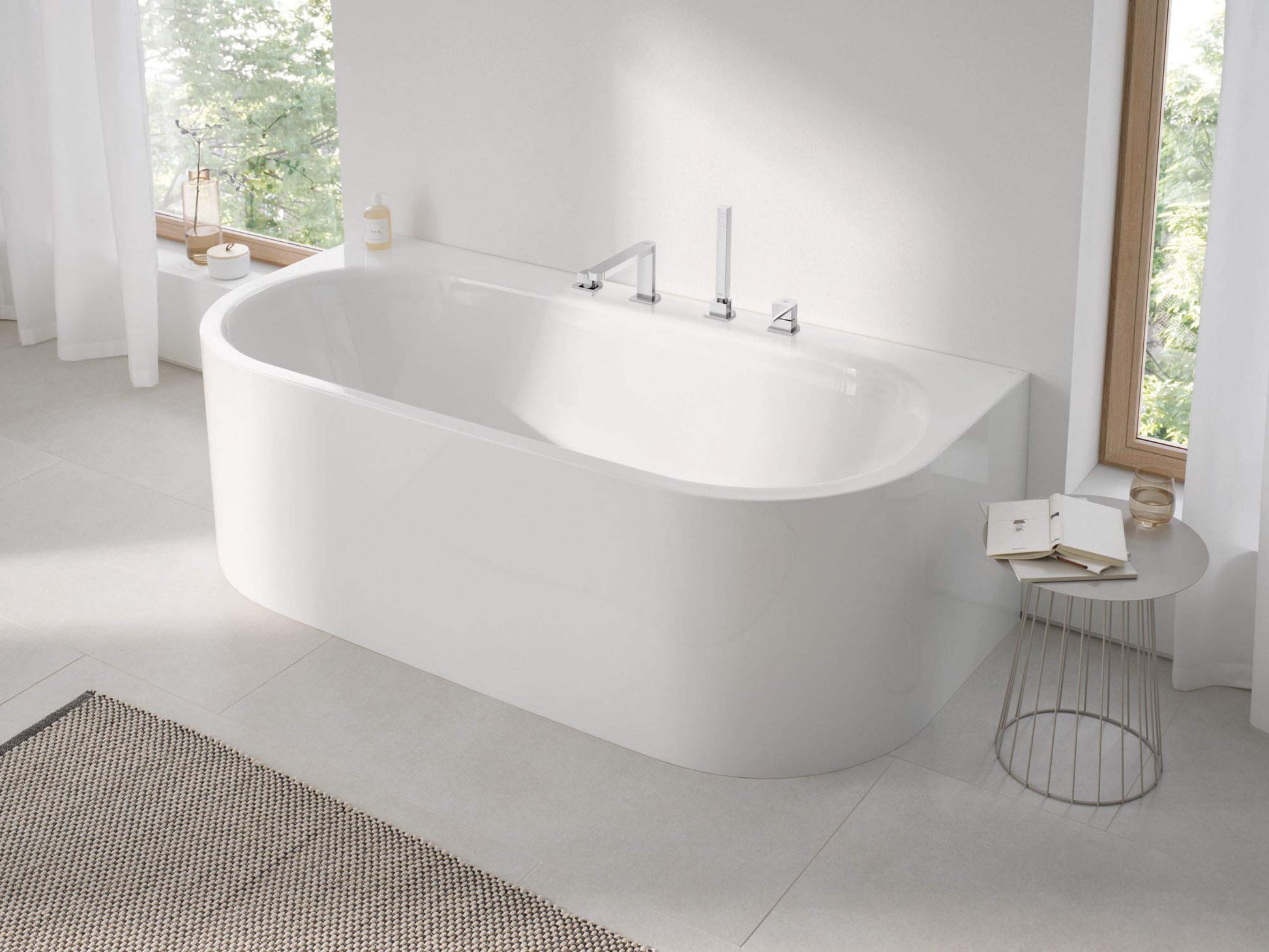 Chrome roman tub faucet with single handle and hand shower mounted on white freestanding bathtub.