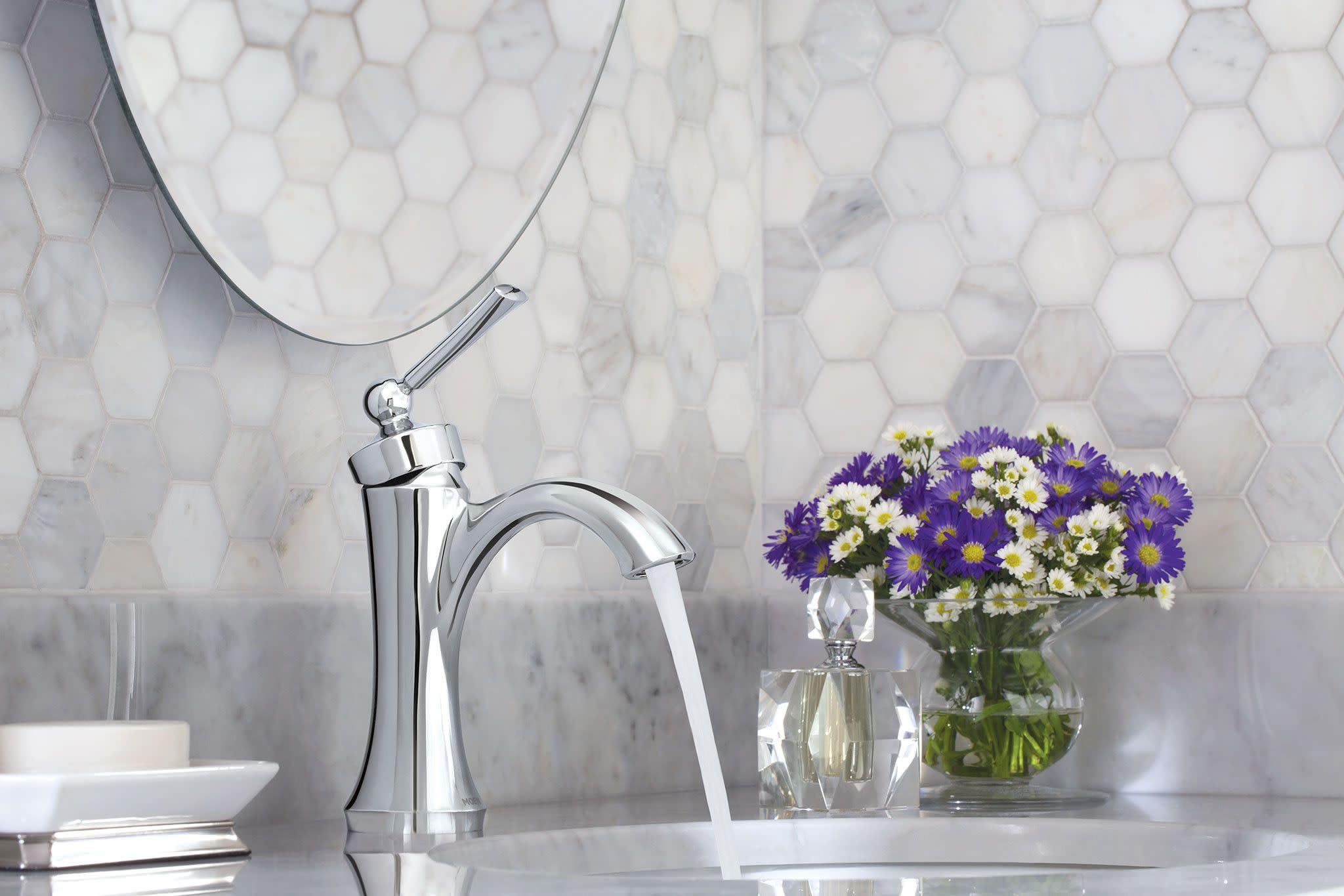 Brushed nickel single-handle high-arc bathroom faucet with water flowing into sink basin, displayed on marble countertop.
