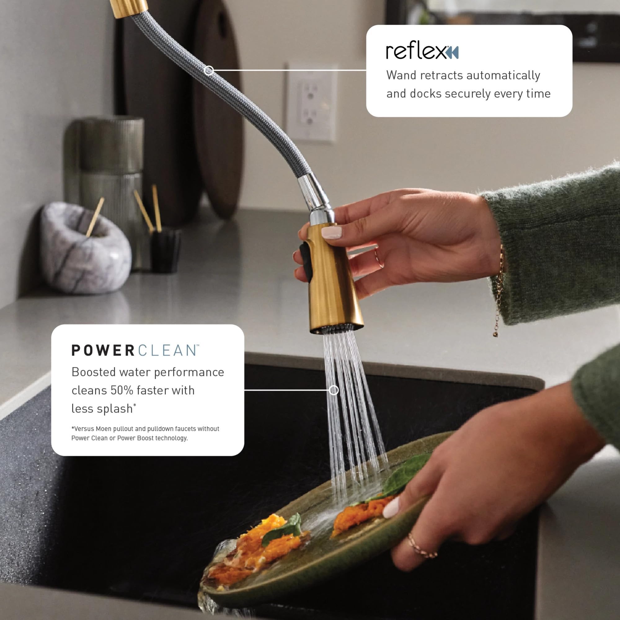Brushed gold pulldown kitchen faucet with flexible hose being used to rinse food in sink.