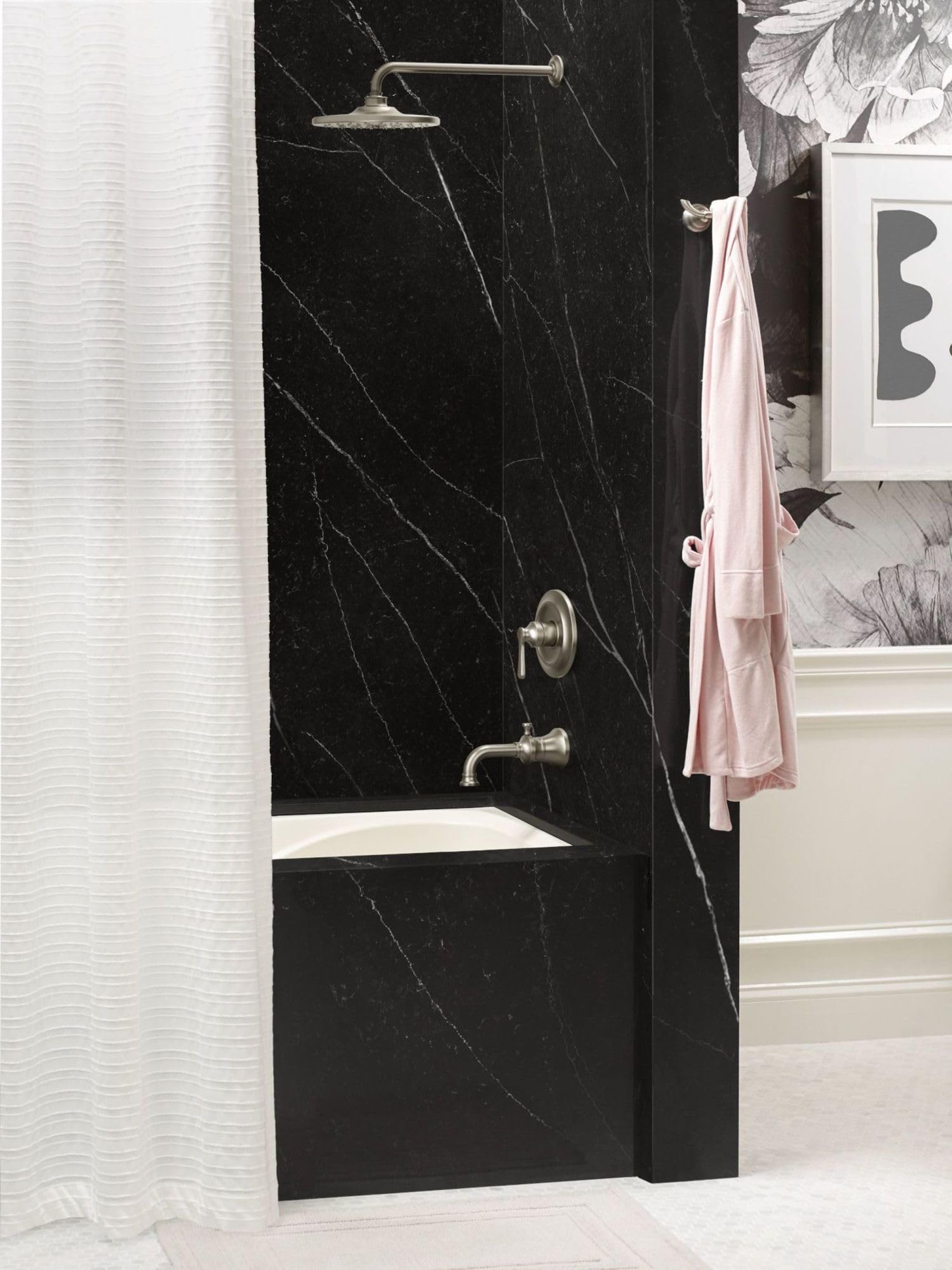 Brushed nickel single-handle tub and shower trim kit mounted on black marble shower wall with showerhead and spout.