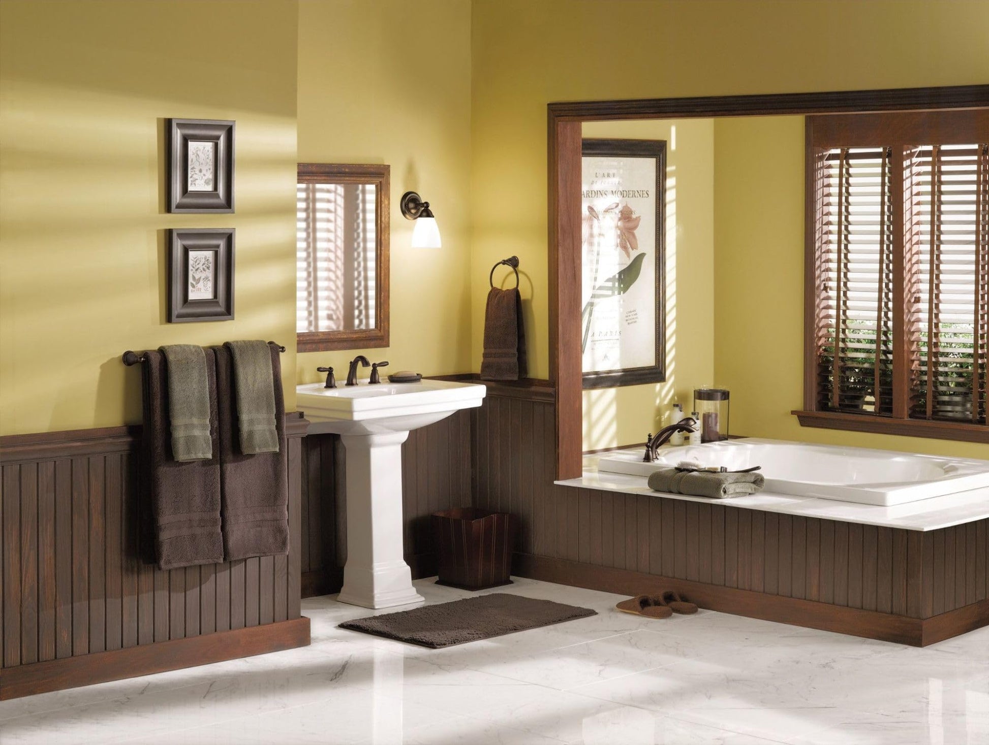 Chrome two-handle deck mount Roman tub faucet trim kit with curved spout installed above white bathtub.