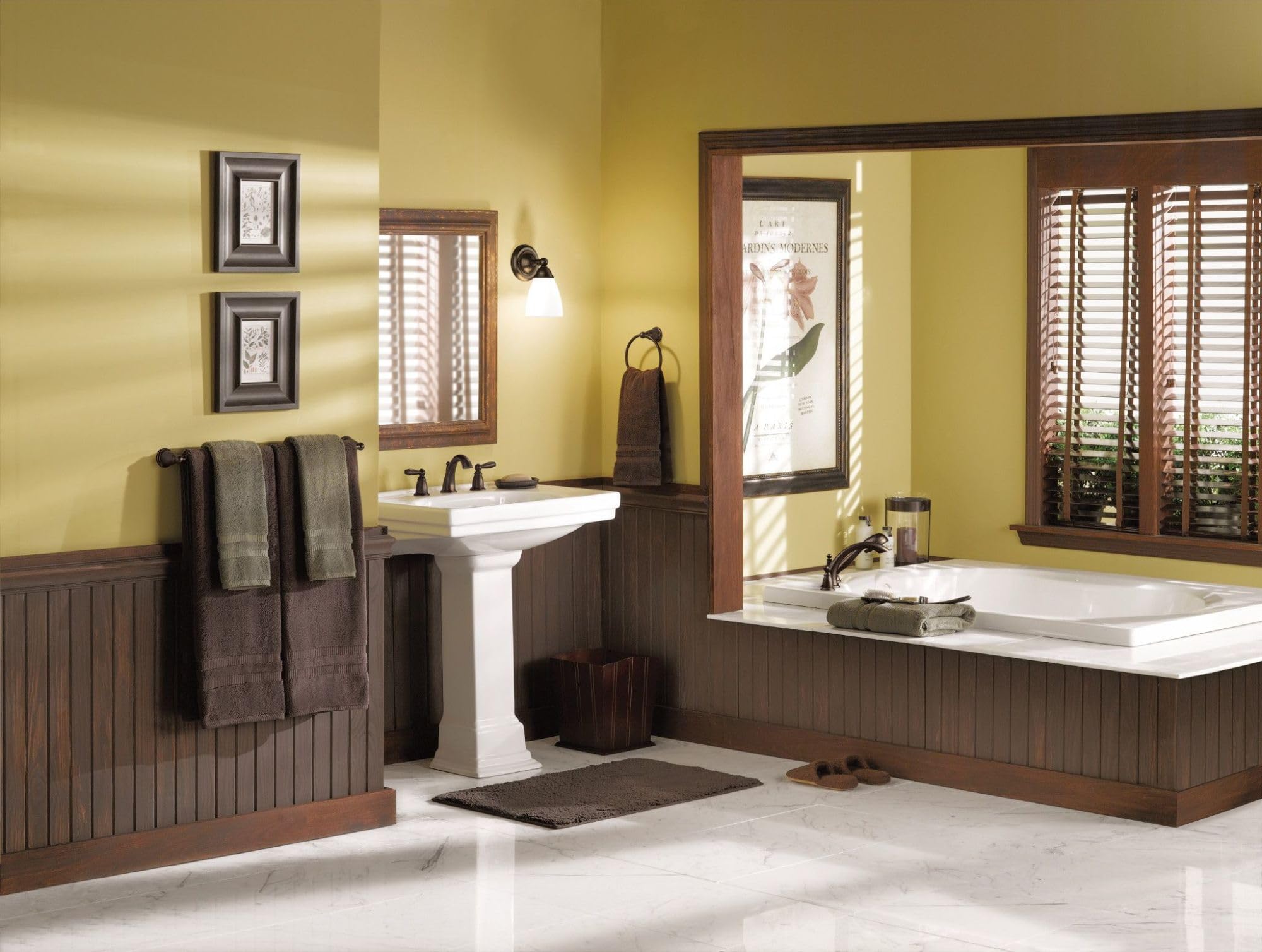 Chrome two-handle deck mount Roman tub faucet trim kit with curved spout installed above white bathtub.