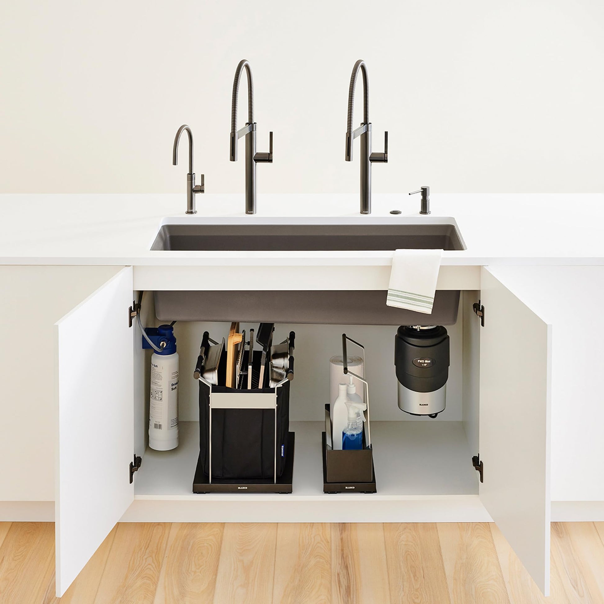 Black under-sink organizer with compartments holding cleaning supplies, utensil holder, and accessories inside white cabinet 