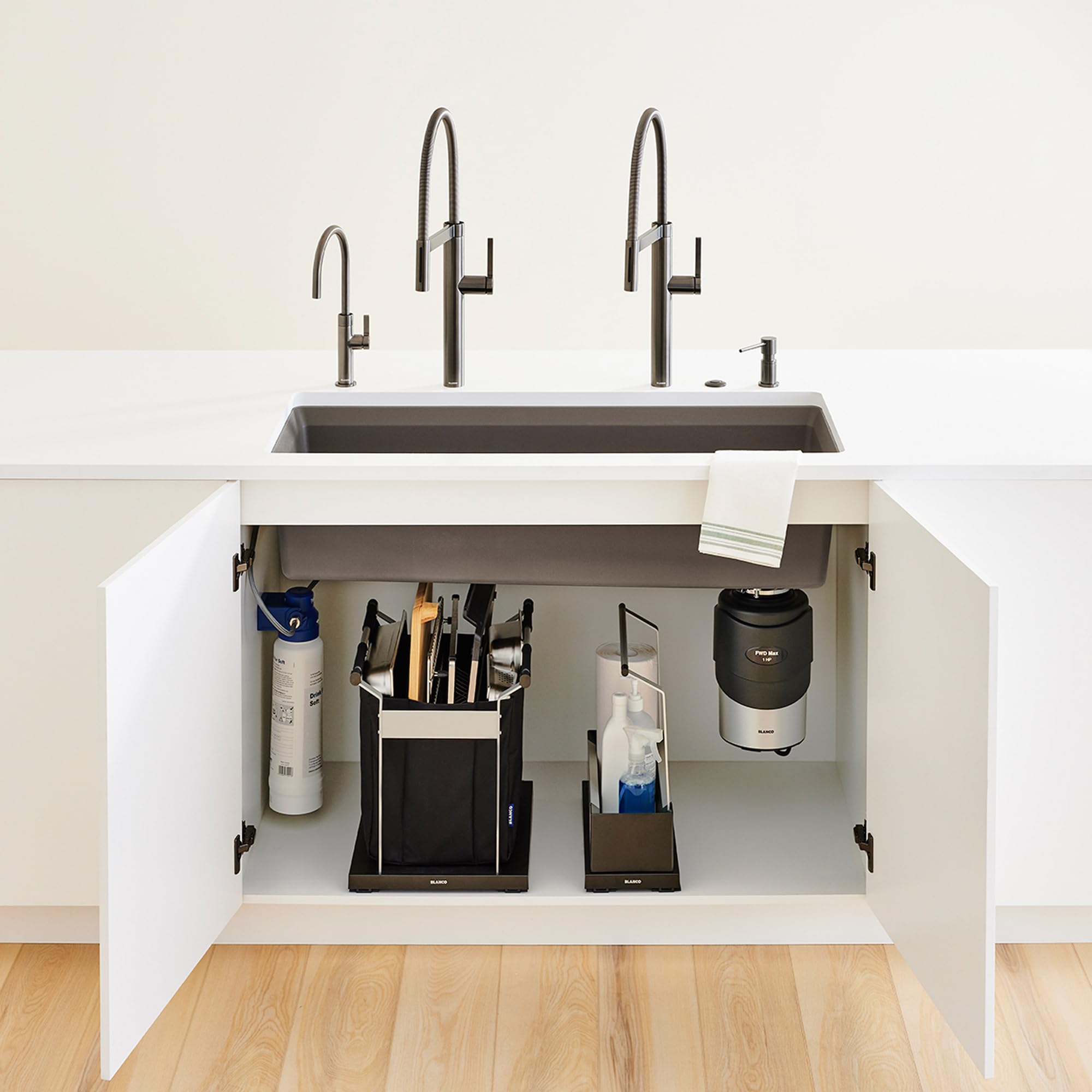 Black under-sink organizer with compartments holding cleaning supplies, utensil holder, and accessories inside white cabinet 