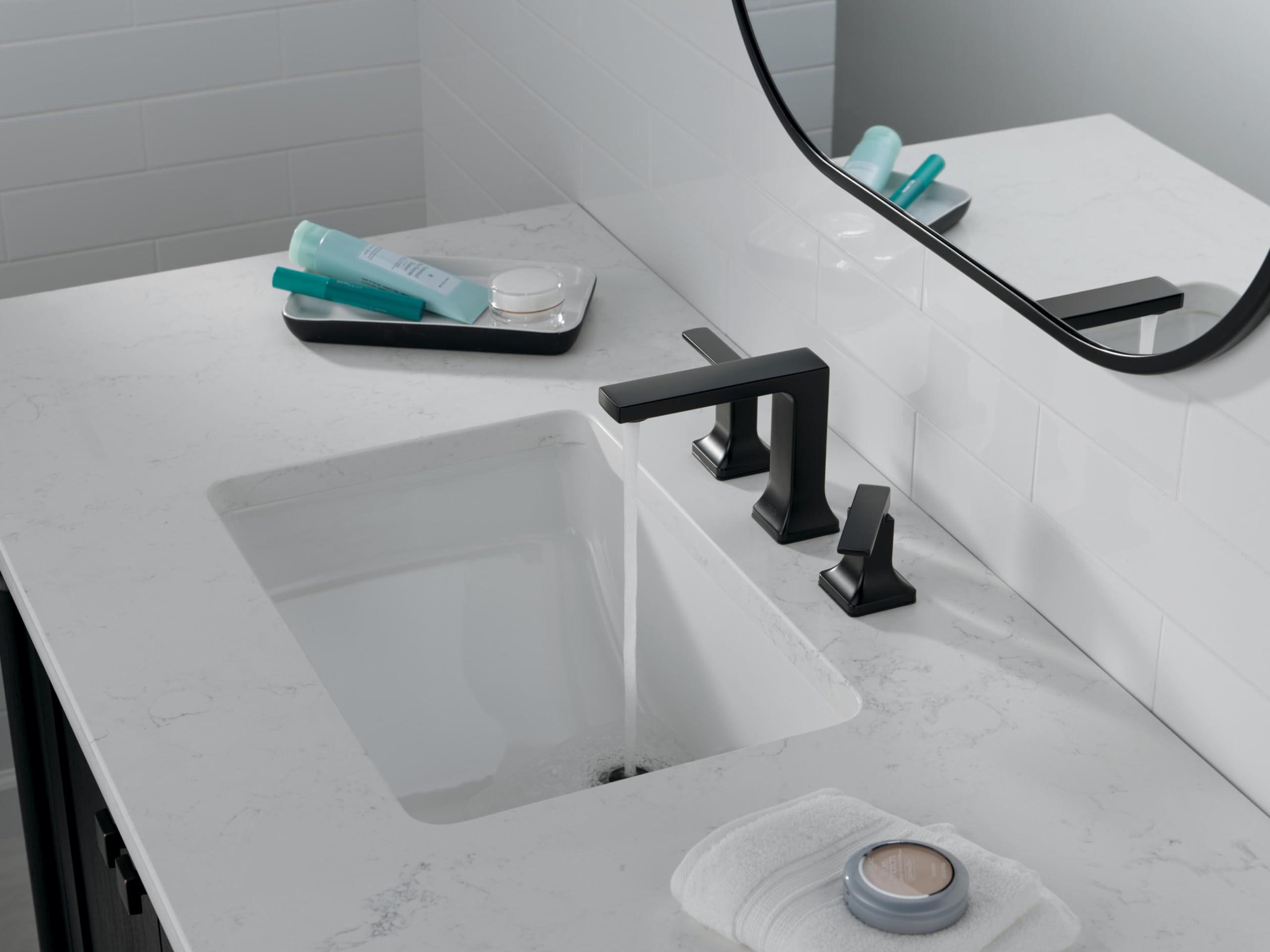 Matte black two-handle widespread bathroom faucet with rectangular spout installed on white marble countertop above sink.