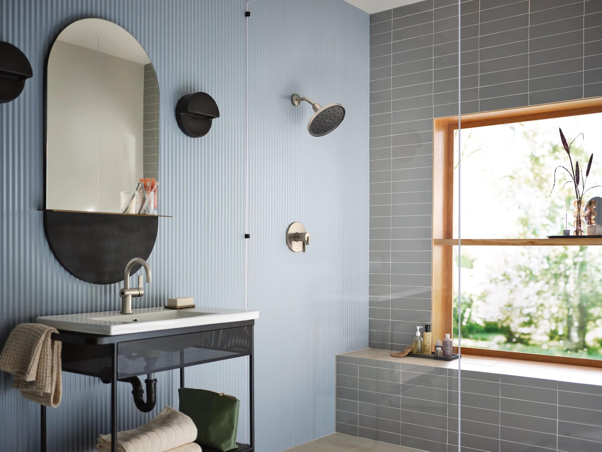 Brushed nickel single-handle bathroom sink faucet with curved spout installed on white sink vanity.