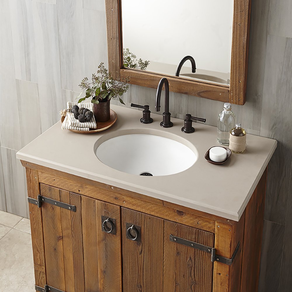 Pearl-colored round bathroom sink with white countertop mounted on wooden vanity with black faucet.