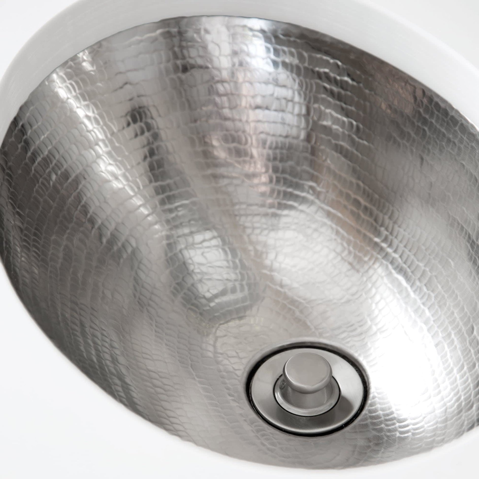 Polished nickel round sink with textured hammered surface and center drain opening.
