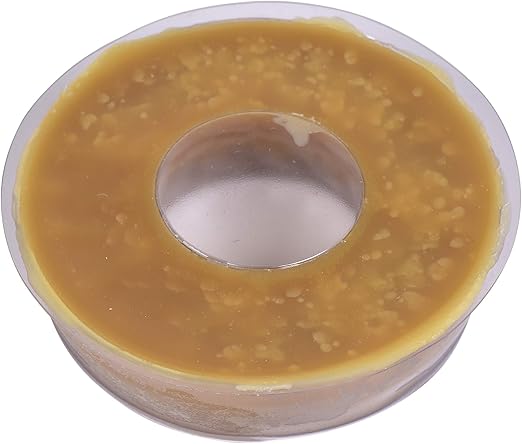 Round tan wax ring with center hole in clear plastic container.