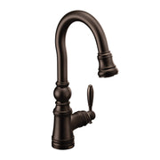 Oil rubbed bronze kitchen faucet with curved pulldown spout and single lever handle.