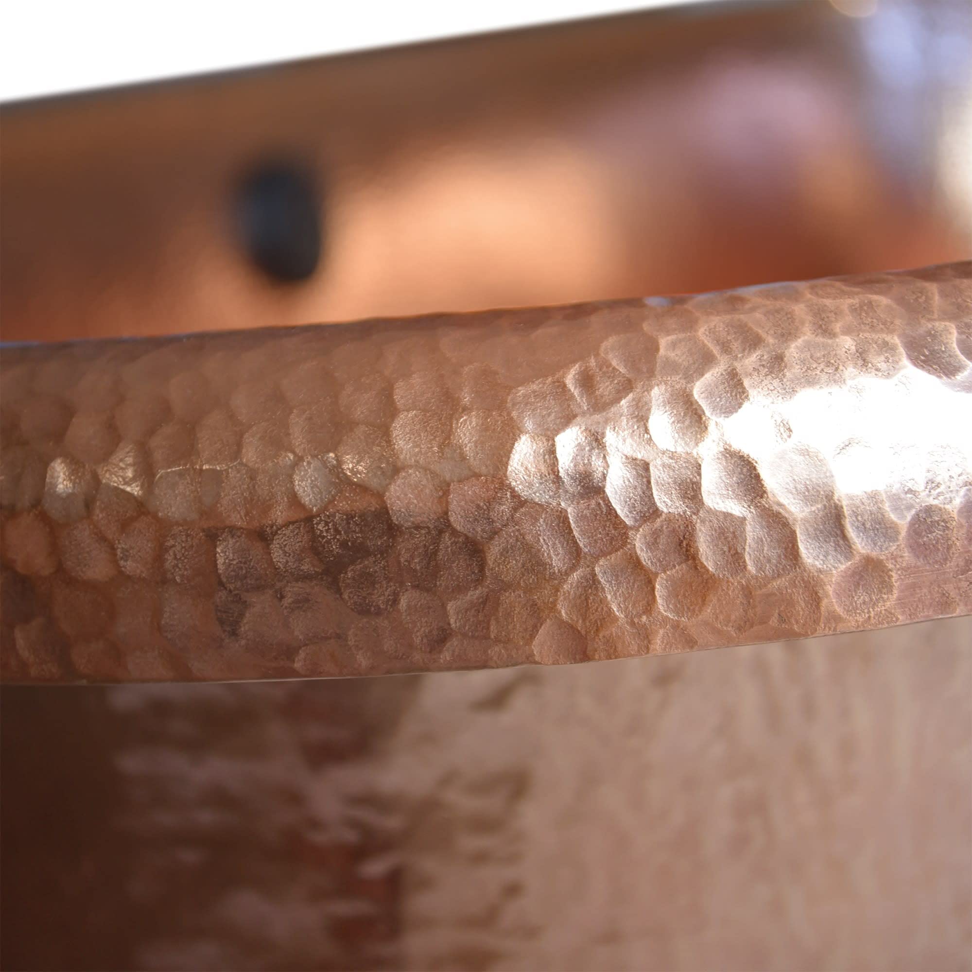 Antique copper bathtub rim with hammered texture and patina finish.