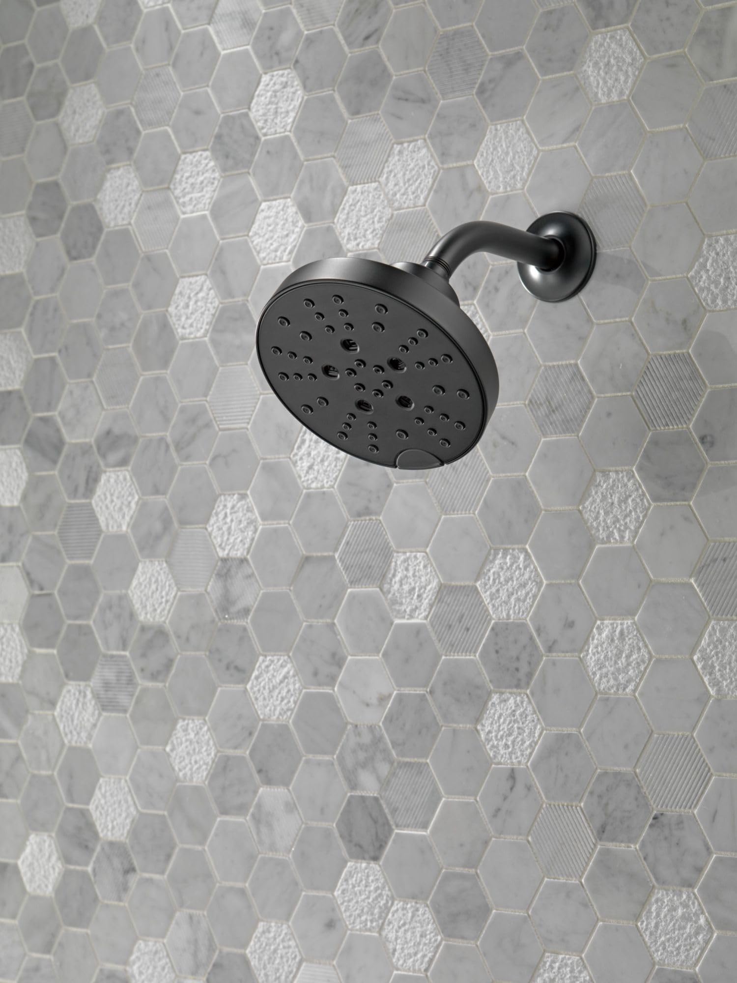 Matte black round shower head with perforated spray holes mounted on curved arm and circular wall flange.
