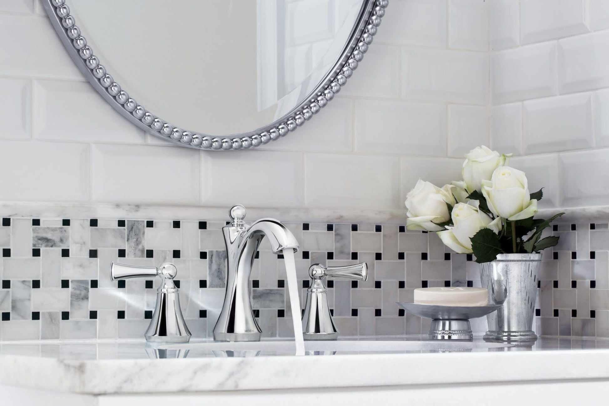 Chrome two-handle widespread bathroom faucet with high arc spout and lever handles on marble countertop.
