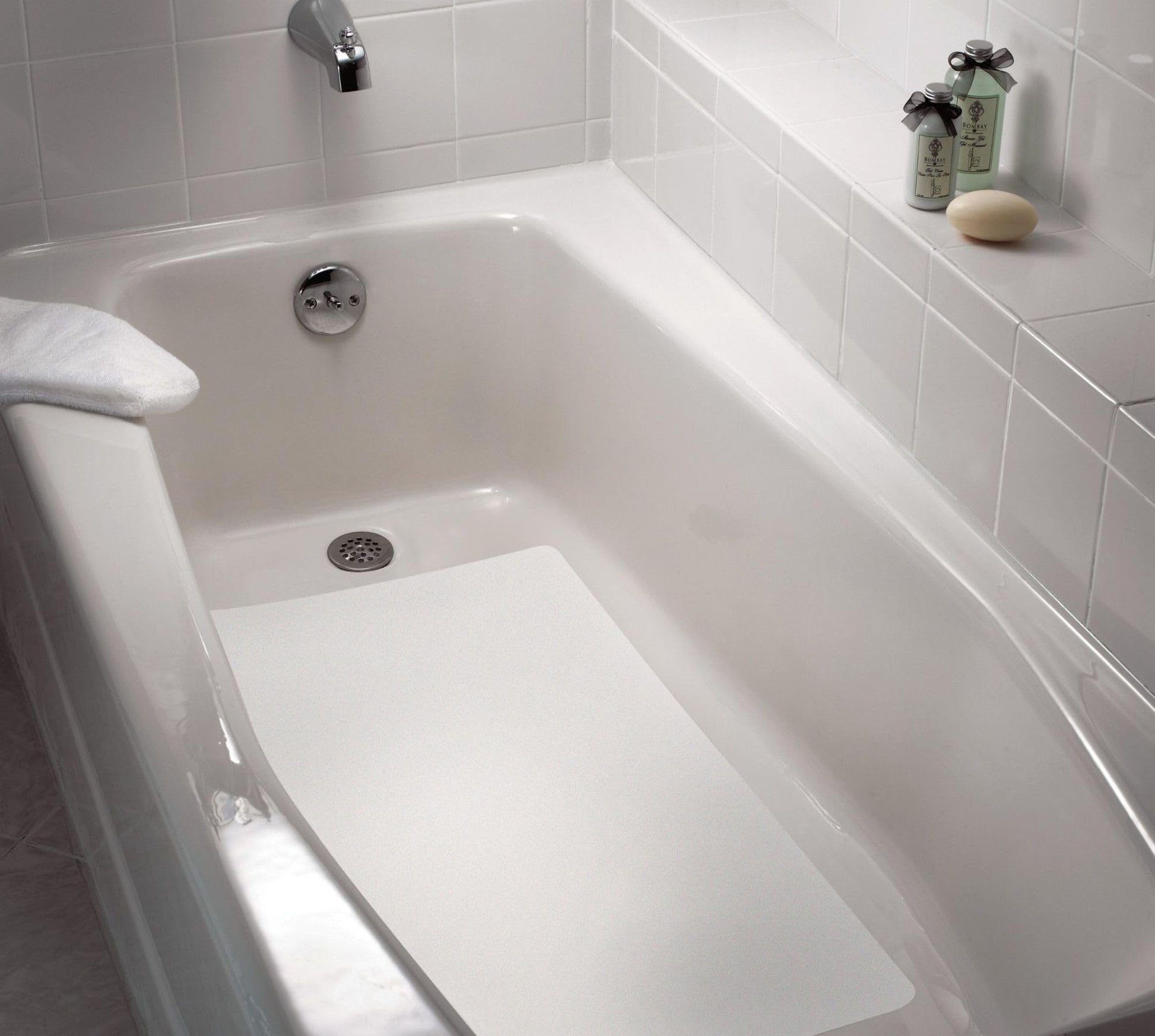 White non-slip bath mat placed in a white ceramic bathtub with tile surround.