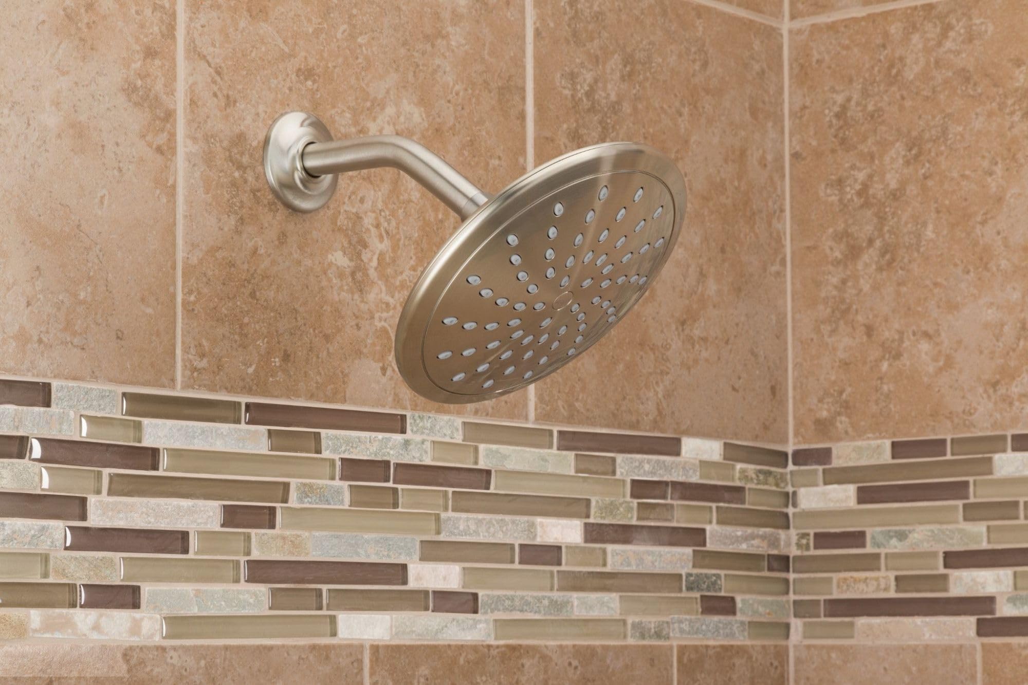 Brushed nickel rain shower head mounted on wall with curved arm, showing spray holes in circular face.