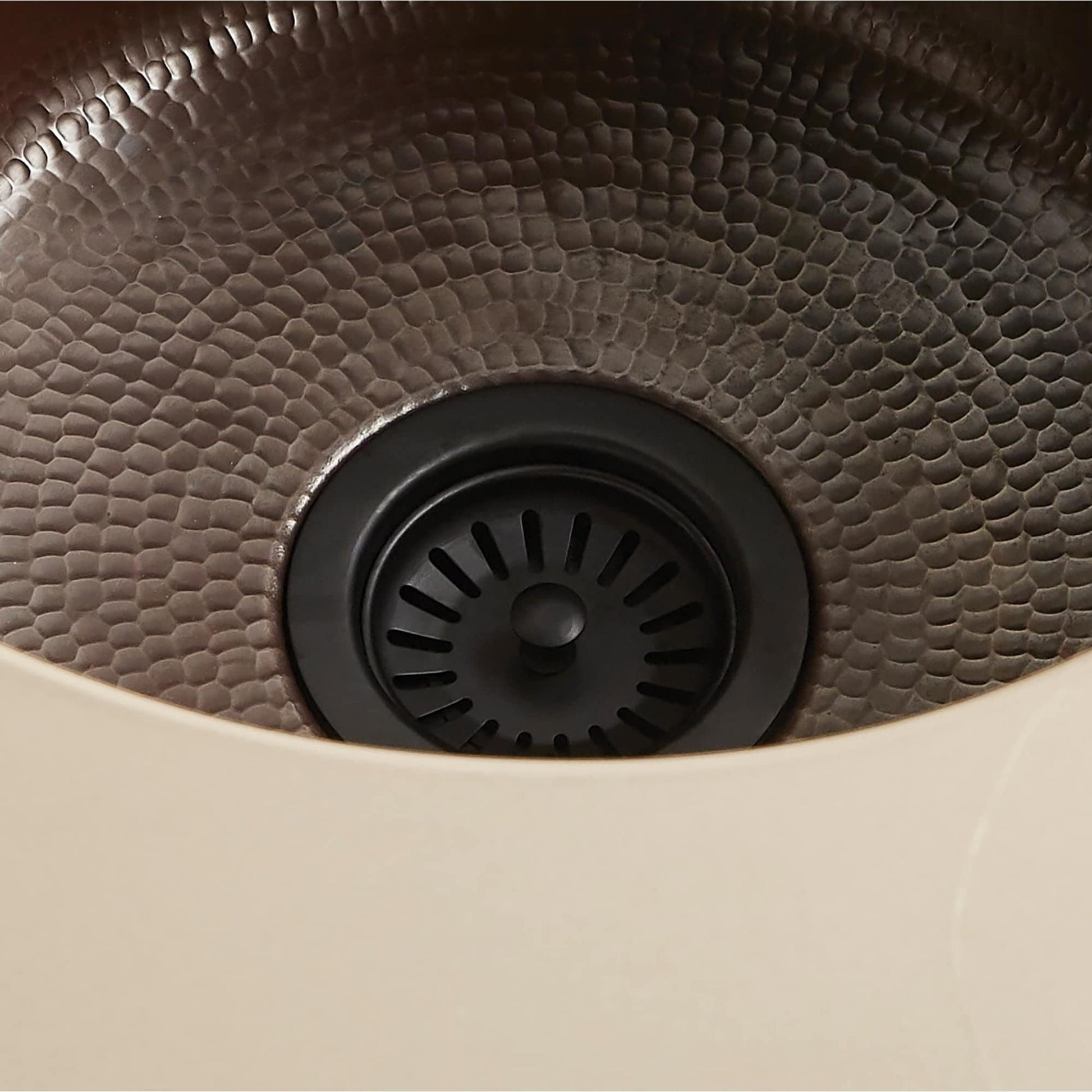 Matte black basket strainer with radial slot pattern and textured hammered bowl interior.