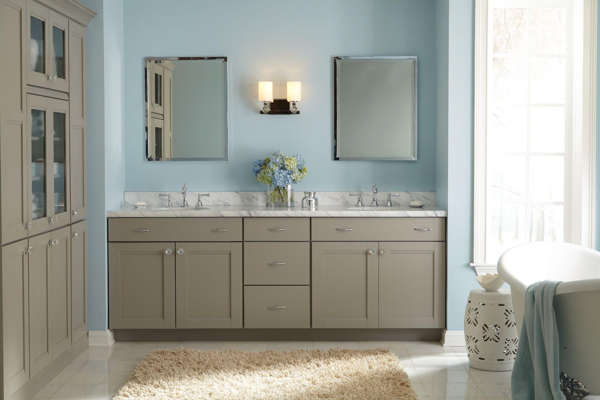 Chrome two-handle widespread bathroom faucet with high arc spout and lever handles mounted on marble vanity.
