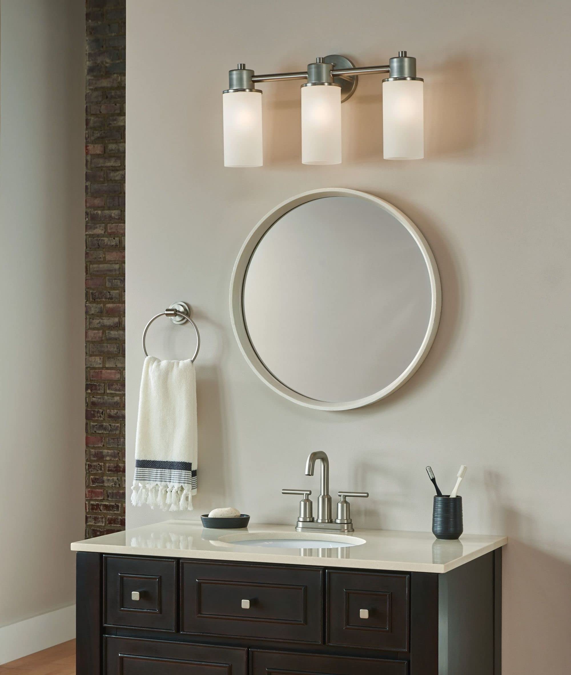 Brushed nickel wall-mount towel ring with circular design, displayed on bathroom wall next to sink vanity.