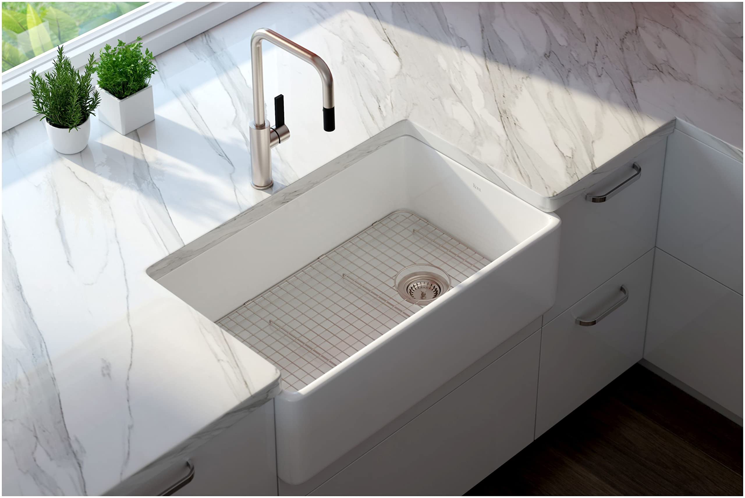 Polished chrome pull-down kitchen faucet with U-shaped spout mounted above white farmhouse sink with grid strainer.