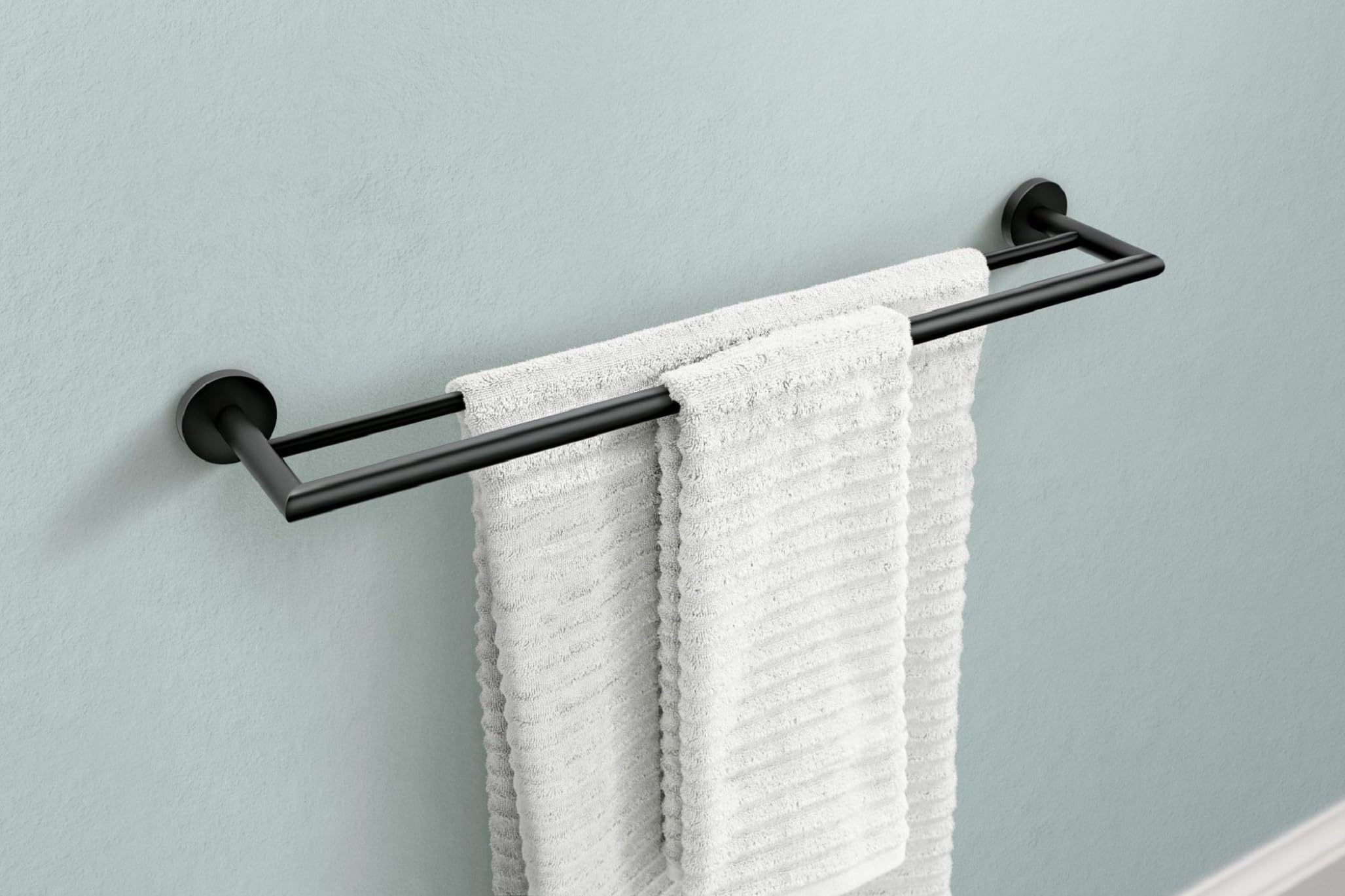 Matte black double towel bar mounted on wall with two white towels draped over horizontal bars.