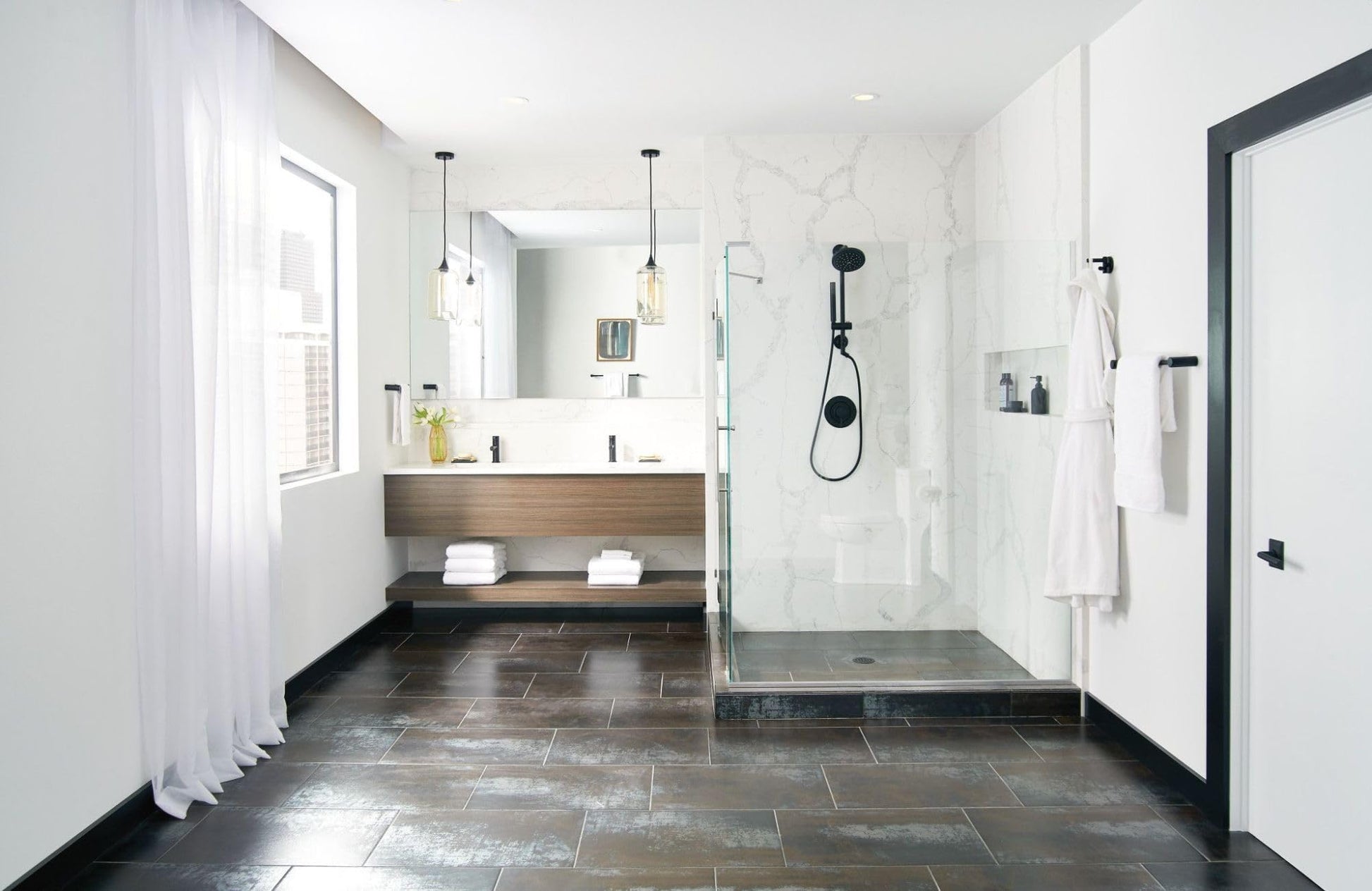 Black hand towel bar mounted on white bathroom wall next to shower enclosure.