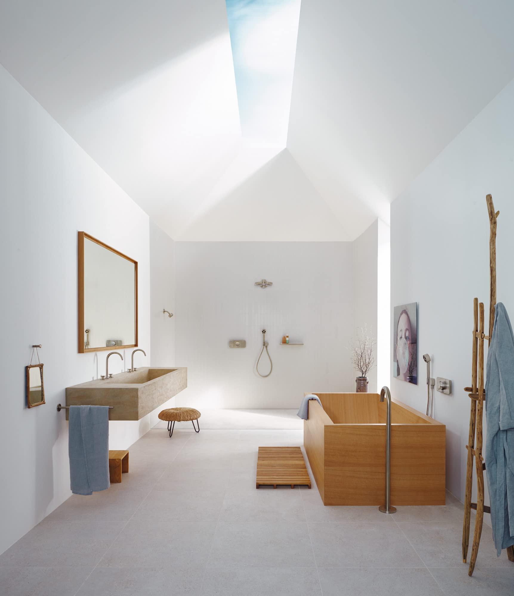 Brushed nickel handshower mounted on shower wall in modern bathroom with wooden tub and floating sink.