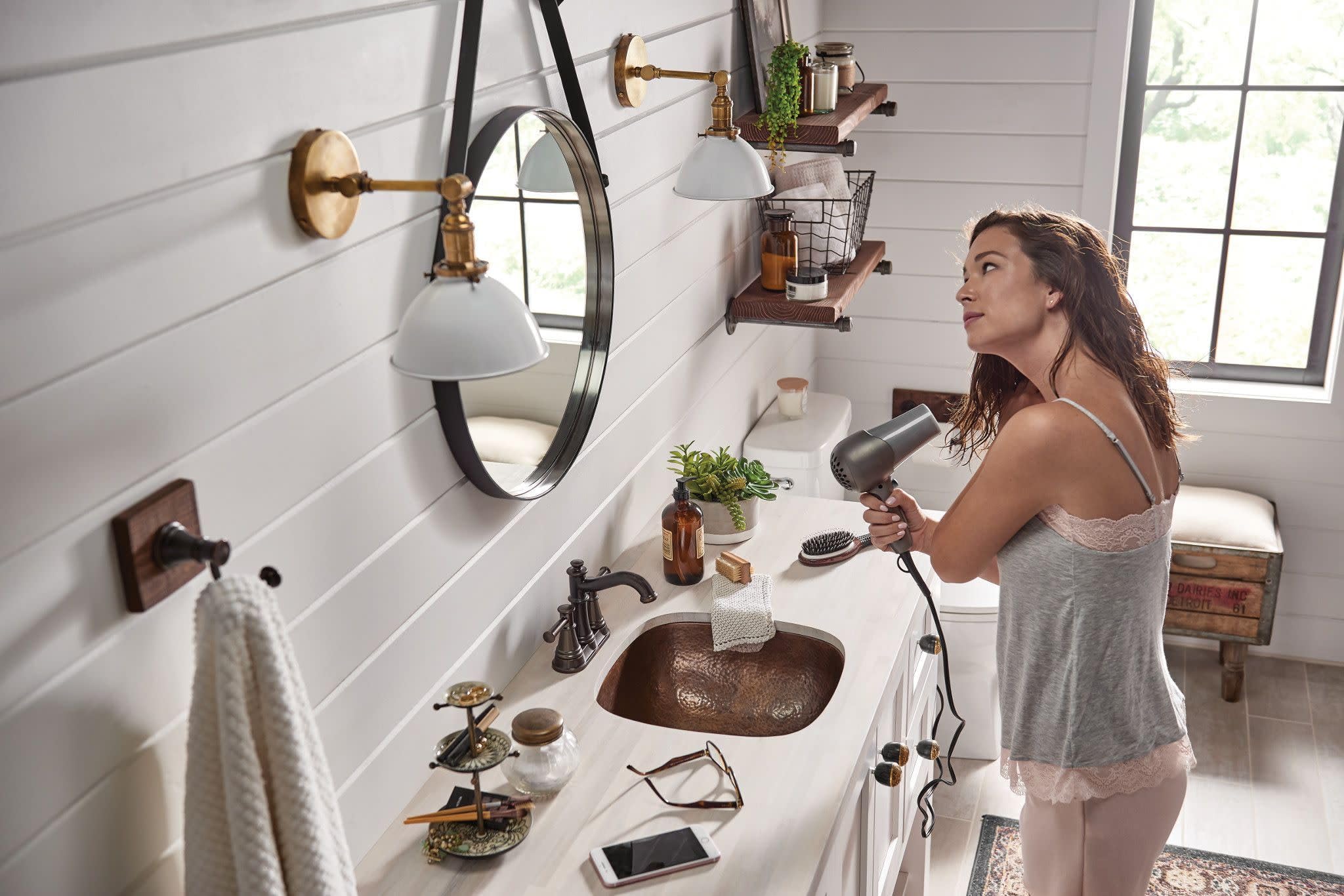 Oil-rubbed bronze two-handle centerset bathroom faucet with curved spout installed on white vanity.