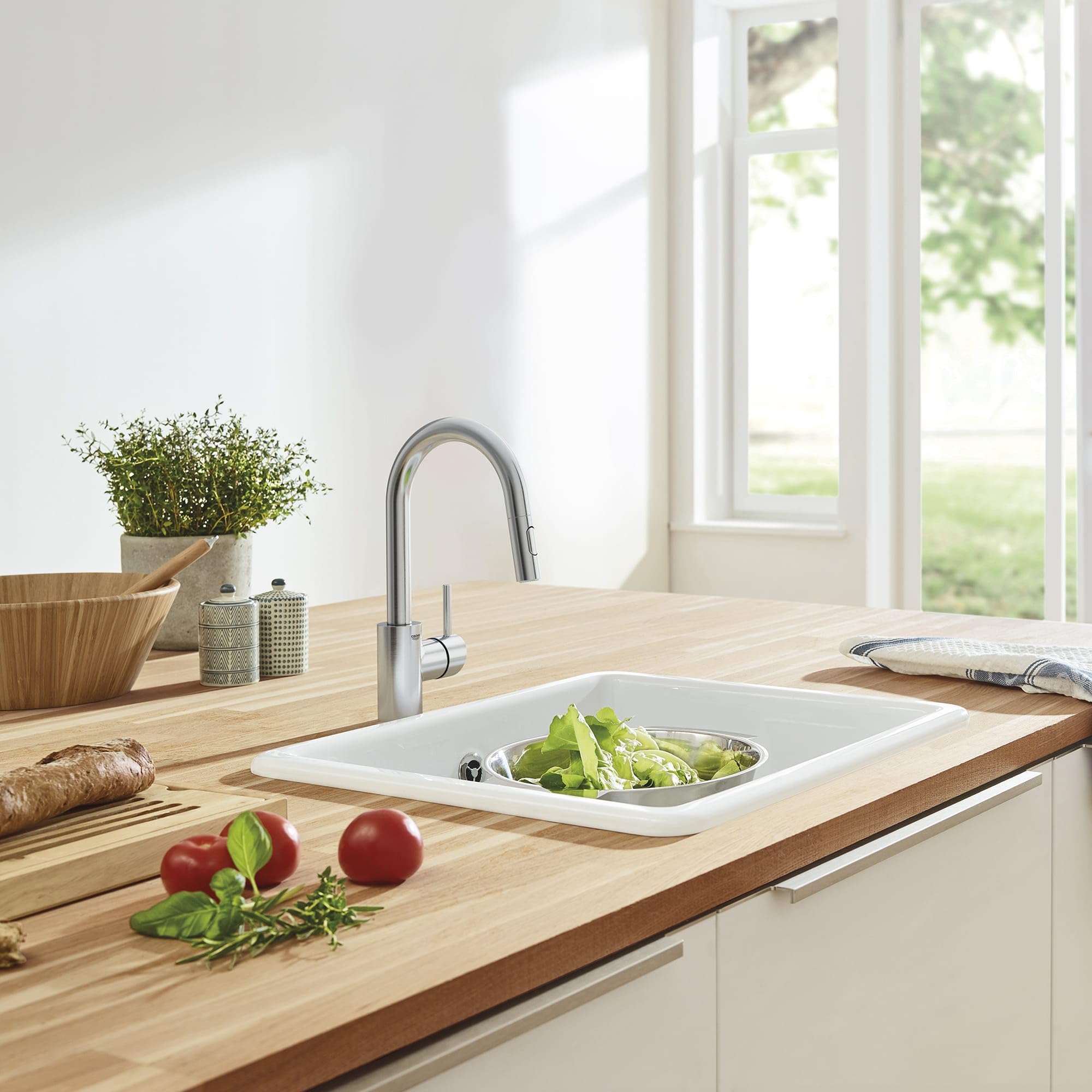 Stainless steel single-handle pull-down bar faucet with curved spout installed above white rectangular kitchen sink.
