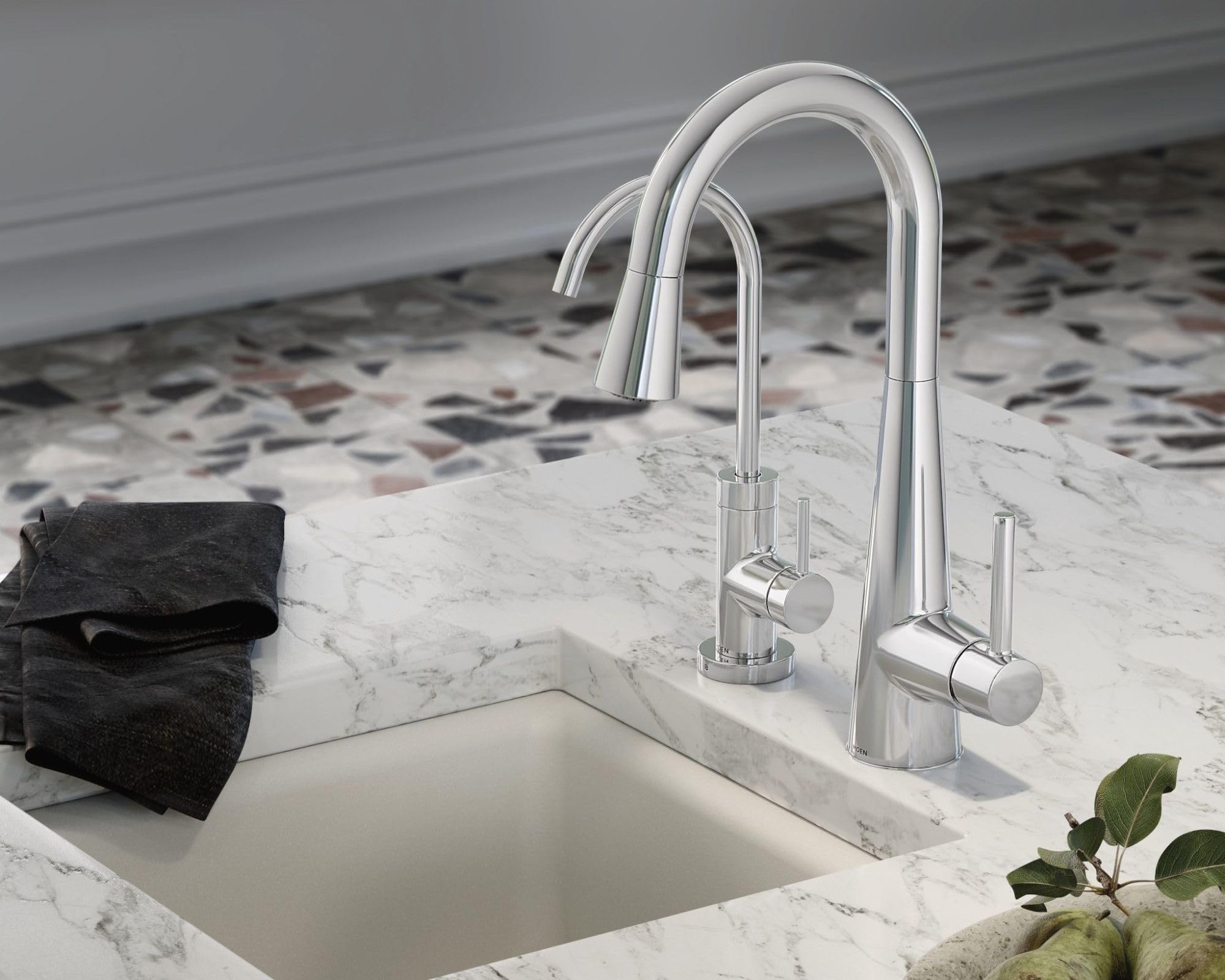 Chrome kitchen faucet with dual curved spouts mounted on marble countertop above white sink.