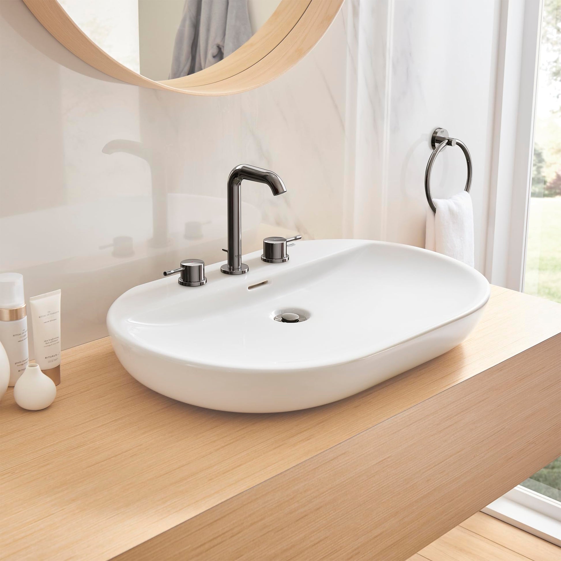Dark graphite two-handle bathroom faucet with curved spout mounted on white oval sink.