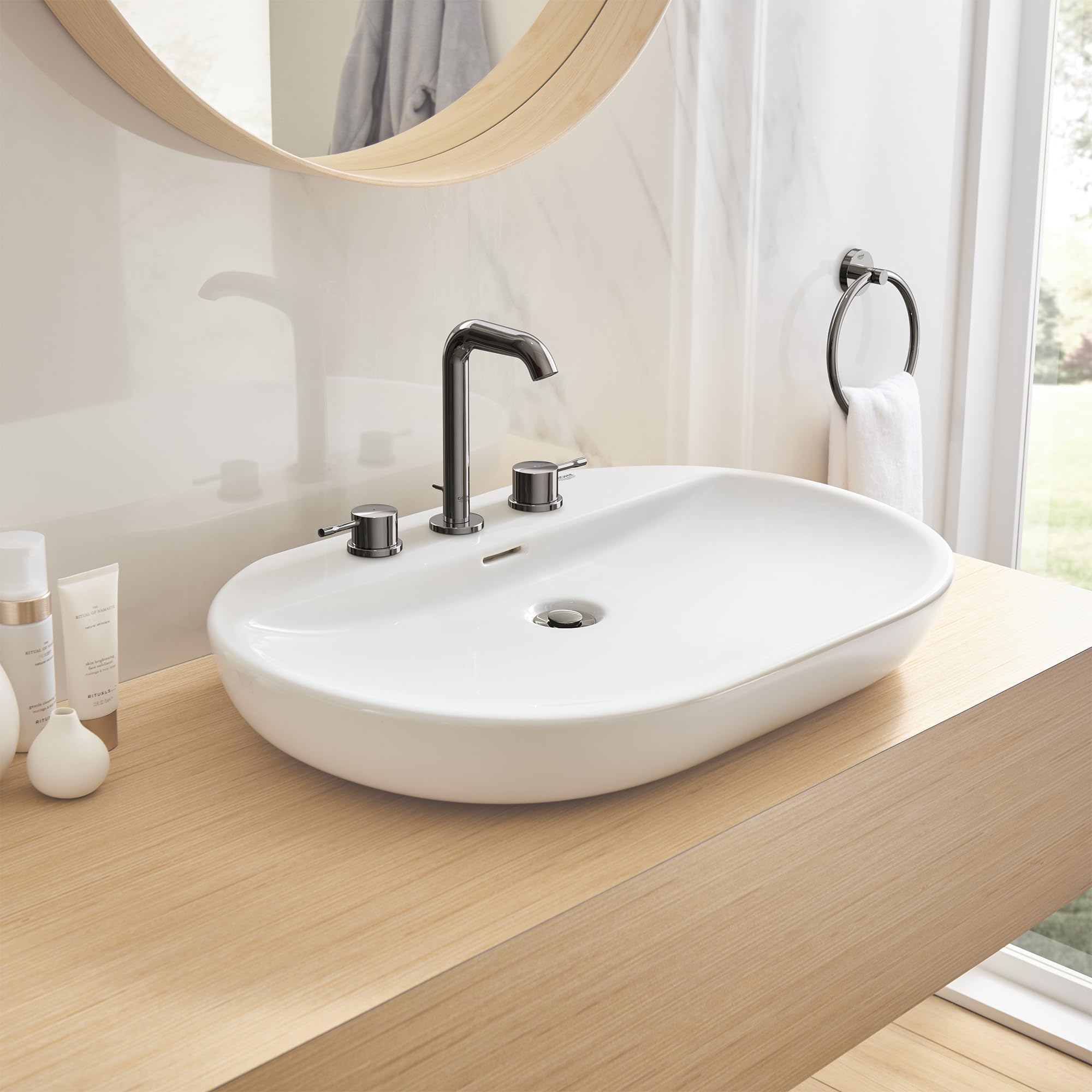 Dark graphite two-handle bathroom faucet with curved spout mounted on white oval sink.