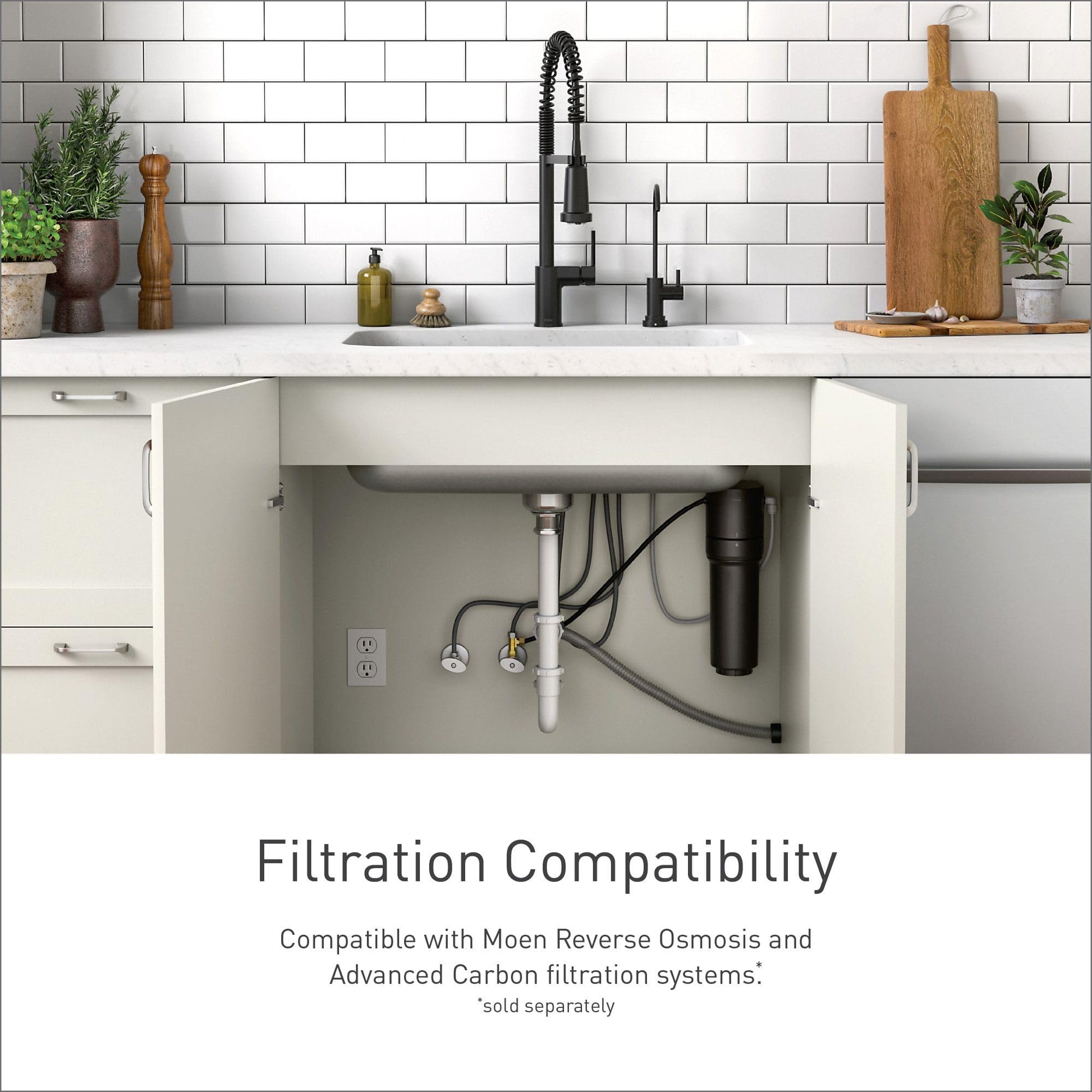 Black Moen drinking water faucet with pull-down sprayer installed on white subway tile backsplash, shown with under-sink filt